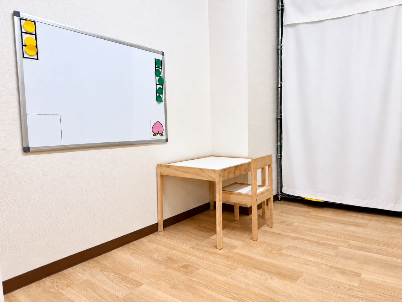 木の机といすとホワイトボードがある、もものお部屋